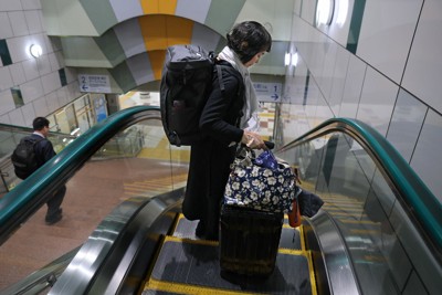東京での過労死等防止対策推進シンポジウムに出席するため、香川県から羽田空港に到着し、大きなリュックやスーツケースを持って移動する高橋幸美さん＝東京都大田区で2025年11月5日、佐々木順一撮影