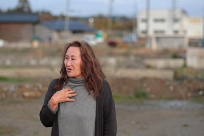 能登半島地震で半壊となり、公費解体した自宅跡地に立つ室谷美恵子さん。自宅があった蛸島地区は空き地が広がる＝石川県珠洲市で2025年12月2日、岩本一希撮影
