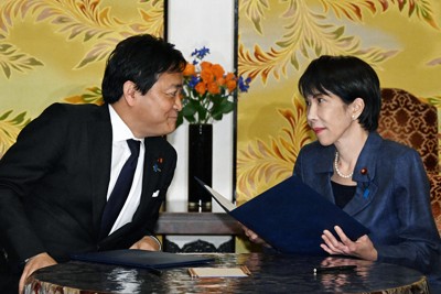 「年収の壁」をめぐる合意文書を手に言葉を交わす高市早苗首相と国民民主党の玉木雄一郎代表（国会内で2025年12月18日）