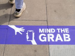 スマートフォンひったくりへの注意を呼びかける路上の表示＝ロンドンで2025年8月、ロイター