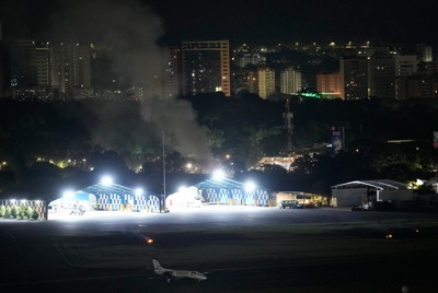 ベネズエラの首都カラカスで爆発、煙が上がるラ・カルロタ空港＝2026年1月3日、AP