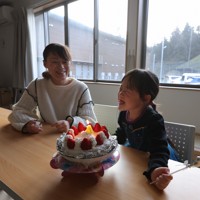 仮設住宅の集会所で長女・仁那ちゃん（右）の4歳の誕生日を祝うシングルマザーの脇田友里恵さん。お店で売っていたケーキは高価だったため手作りし、仮設住宅の敷地で遊べるようにスノーブーツとキックスケーターをプレゼントした＝石川県珠洲市で2025年12月28日、中川祐一撮影