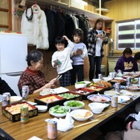 輪島市の渋洞福子さん一家は元旦、2年ぶりに親族が集まった。家は土砂ダムの影響で水没。現在は離れを改装して住んでいて、玄関にマットを引いて親族が座る場所を確保した。「2年前の続きができたみたい。みんな元気で1年を過ごしたい」＝石川県輪島市で2026年1月1日午後0時36分、滝川大貴撮影