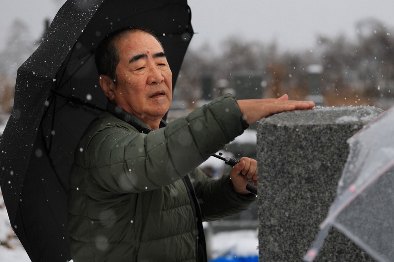 地震で母と兄を亡くし、雪が降った命日の朝、墓の雪を払う舩本悦司さん（70）は「母は元気だったから。地震さえなければもっと長生きできたのにと思わずにはいられない。向こうで皆仲良く過ごして欲しい」と悼んだ＝石川県珠洲市で2026年1月1日午前9時23分、滝川大貴撮影