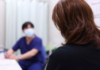 This April 2022 file photo shows a woman being seen by a doctor in Osaka's Kita Ward. (Mainichi/Maiko Umeda)