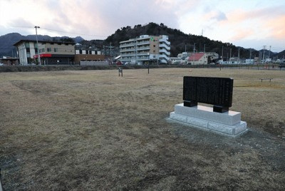 震災当時の役場庁舎跡地に建つ石碑（右手前）。跡地はほぼ当時のままの地面高で緑地となっている＝岩手県大槌町で2026年1月6日、奥田伸一撮影
