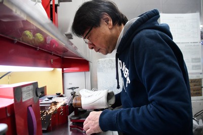 スケート靴のエッジを研磨する田山裕士さん＝大阪市北区の小杉スケート梅田本店で2025年12月29日午後0時35分、玉井滉大撮影