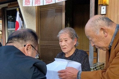 DNA鑑定で父細川利男さんと判明した遺骨を徳島県職員（左）から受け取る青山誠子さん（中央）＝徳島県美馬市で2025年12月23日、植松晃一撮影