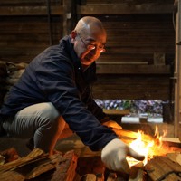 再建した窯の火入れの日、徐々に勢いを増す炎にまきをくべる篠原敬さん＝石川県珠洲市で2025年12月25日、岩本一希撮影
