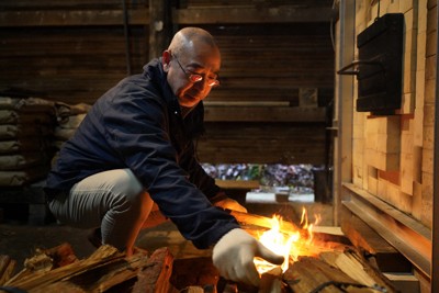再建した窯の火入れの日、徐々に勢いを増す炎にまきをくべる篠原敬さん＝石川県珠洲市で2025年12月25日、岩本一希撮影