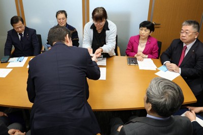 長生炭鉱で収容された遺骨問題で、犠牲者のDNA型情報が入ったUSBメモリーを政府の担当者（手前）に渡す市民団体「長生炭鉱の水非常を歴史に刻む会」の井上洋子代表（中央奥）＝国会内で2026年1月20日午後0時4分、後藤由耶撮影