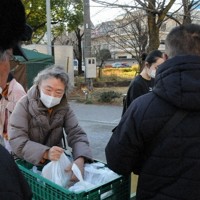 Members of "Asile" hand out free boxed meals to people lining up in Sumida Park's Sanyabori square in Tokyo's Taito Ward on Jan. 18, 2026. (Mainichi/Atsuhiko Kimura)