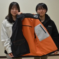 防災のためのアイデアが満載のベスト。完成品の出来に満足する福井高専の新井葵々さん（右）と高嶋加凛さん＝福井県鯖江市で2025年12月23日午後6時15分、萱原健一撮影