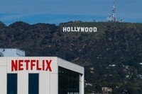 A Netflix sign is displayed atop a building in Los Angeles, on Dec. 18, 2025, with the Hollywood sign in the distance. (AP Photo/Jae C. Hong, File)