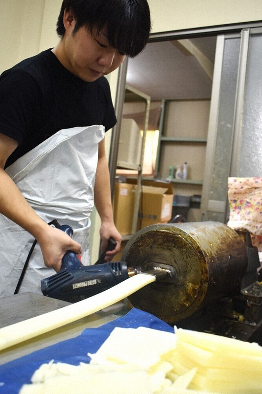 作業中の山口大貴さん。専用器具で成形機の出口を熱し、びんつけ油が出やすいよう滑りをよくしている