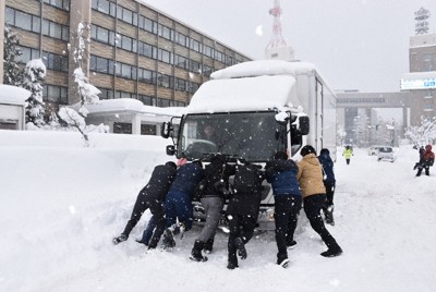 立ち往生していた4トントラックを押して手助けする人たち＝青森市の青森県庁前で2026年1月23日午後0時31分、松本信太郎撮影