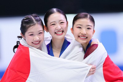 笑顔で抱き合う女子1位の青木祐奈（中央）、2位の中井亜美（左）、3位の千葉百音＝中国・北京の国家体育館で2026年1月23日、吉田航太撮影