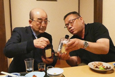 旧吉野村出身の清水一也さん（左）に、吉野1号で造った酒「旅」の特徴について説明する羅己能さん＝群馬県高崎市で2025年3月12日、鈴木玲子撮影