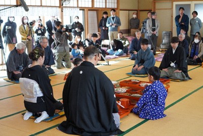 地区住民らが見守るなか、祝いの膳を前に固めの杯を交わす「新成人」の平凌大さん（中央右）＝栃木県日光市川俣で2026年1月24日
