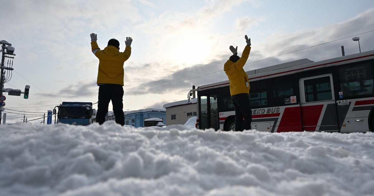 衆院選が公示され、雪が積もった街頭に立ち手を振り支援を訴える選挙スタッフ＝北海道倶知安町で2026年1月27日午前9時11分、宮間俊樹撮影