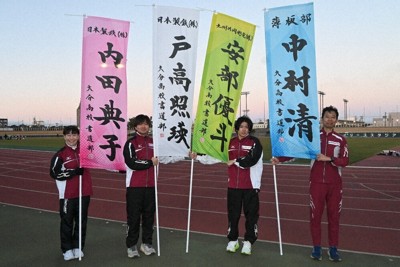 日本製鉄九州製鉄所大分地区陸上競技部の選手と中村清さん（右端）。のぼり旗は大分高校書道部が揮毫した＝大分市で2026年1月22日、山口泰輝撮影