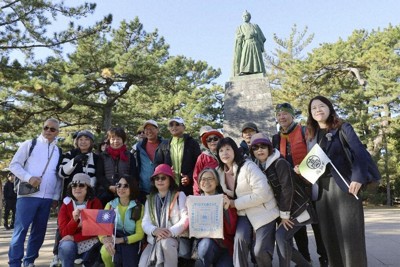 桂浜の坂本龍馬像前で記念撮影に納まる台湾からの観光客＝高知市で2025年12月15日、共同