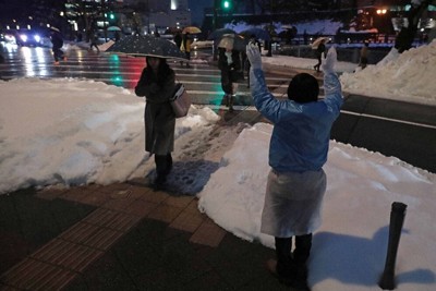 衆院選が公示され、雪の残る交差点に立って行き交う人に手を振る選挙スタッフ＝福井市で2026年1月27日午後5時38分、岩本一希撮影