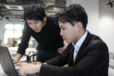 起業した自社の事業について説明する近畿大経済学部4年の越智健心さん（右）。左は起業推進室の垂見俊秀さん＝大阪市鶴見区で2025年12月、共同