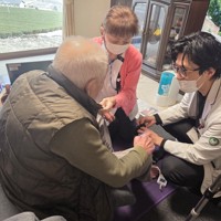 90代男性の自宅を訪問し、男性の足を触る野尻基医師（右）＝岐阜県白川町で2026年1月29日、宇多川はるか撮影