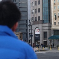 朝の街頭演説をする候補者。奥のビルは大学入試の会場として利用される＝広島市で、安徳祐撮影
