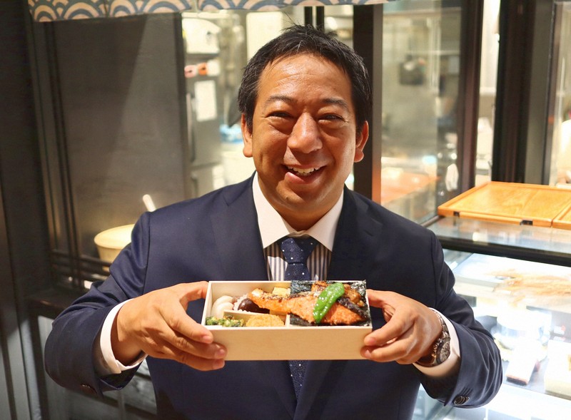 「八重八」の弁当を手にする山岡照幸ヤンマーホールディングス執行役員。同氏が社長を務めるヤンマーマルシェが運営しており、コメなど素材にこだわり昼時には行列ができる＝東京都中央区で2025年9月4日午後3時