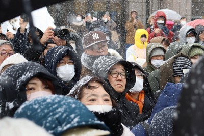 雪が降る中、フードを深くかぶって街頭演説を聞く支持者ら＝札幌市中央区で2026年1月31日午後1時12分、後藤佳怜撮影