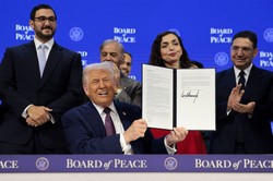 「平和評議会」の設立に関する文書に署名し、笑顔で文書を掲げるトランプ米大統領＝スイス・ダボスで2026年1月22日、ロイター