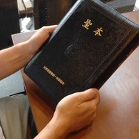 教祖・文鮮明氏の言葉を集めた「聖本」を手に取る元2世信者の男性＝宮城裕也撮影