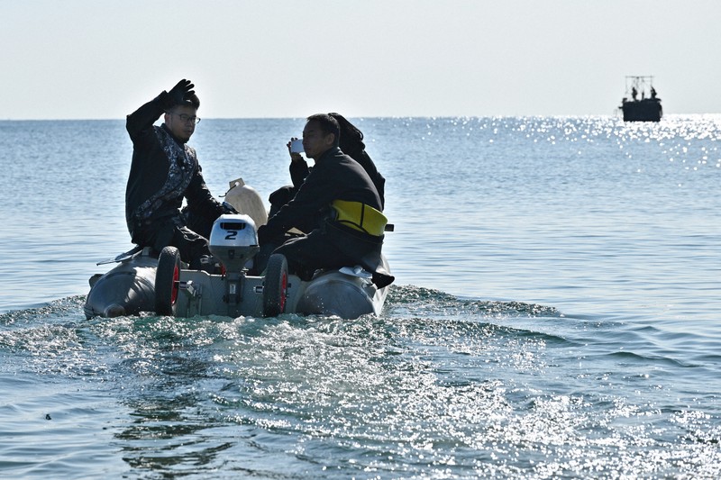 長生炭鉱に残る遺骨収容のため、海面に突き出た円筒「ピーヤ」に向かう水中探検家の伊左治佳孝さん（左）ら＝山口県宇部市で2026年2月3日午前10時28分、北山夏帆撮影