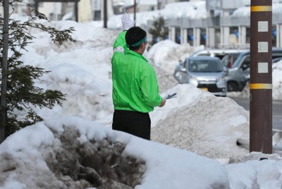腰以上の高さまで雪が残る中、道行く車に手を振る陣営の運動員＝福井県敦賀市で2026年2月5日午後1時25分、岩本一希撮影