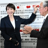 自民党開票センターで、当選確実となった候補者に花をつける高市早苗首相（左）。右は古屋圭司選対委員長＝同党本部で2026年2月8日午後9時42分、平田明浩撮影