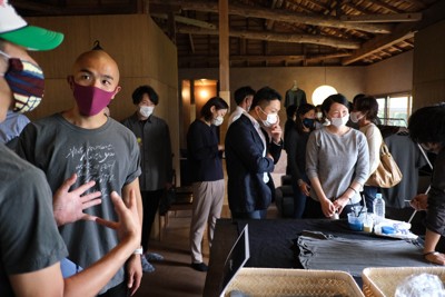 自身のエンディングパーティーで参加者と話す槇仁彦さん（左から2人目）。右はメッセージを添えて参加者に配るTシャツ