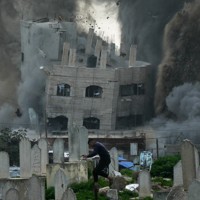 イスラエル軍による攻撃で建物が倒壊する中、逃げる男性＝パレスチナ自治区ガザ地区で2026年2月6日、AP