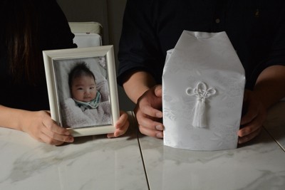認可外保育施設で亡くなった真渚己ちゃんの写真を手に取材に応じる母（左）と父＝東京都内で2025年11月24日午前11時30分、安達恒太郎撮影