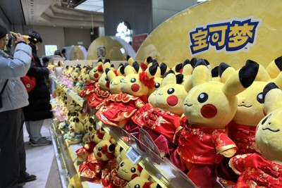 ポケットモンスターのキャラクター「ピカチュウ」のぬいぐるみを眺める人たち。ぬいぐるみは中国風の服を着ている＝北京市で2026年2月6日、畠山哲郎撮影