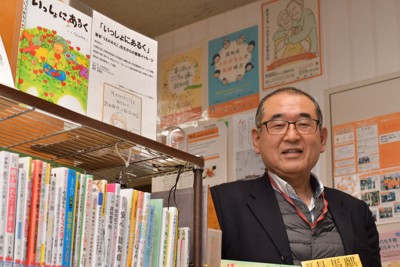 川崎市立宮前図書館に常設されている「認知症の人にやさしい小さな本棚」と舟田彰館長＝同図書館で2026年2月10日午後0時5分、銭場裕司撮影
