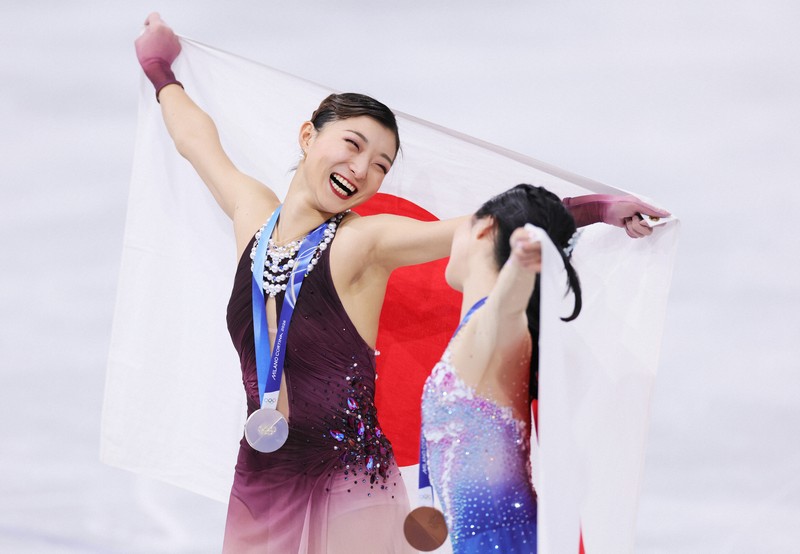 笑顔で3位の中井亜美（右）と見つめ合う2位の坂本花織＝ミラノ・アイススケートアリーナで2026年2月19日、吉田航太撮影