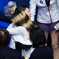 女子フリーでの演技を終えて、米国のアリサ・リュウ（中央手前）と抱き合う坂本花織＝ミラノ・アイススケートアリーナで2026年2月19日、貝塚太一撮影