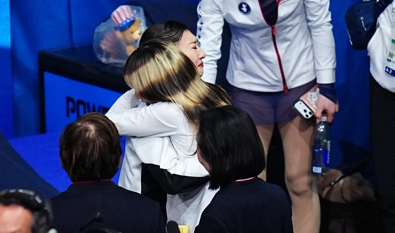 女子フリーでの演技を終えて、米国のアリサ・リュウ（中央手前）と抱き合う坂本花織＝ミラノ・アイススケートアリーナで2026年2月19日、貝塚太一撮影