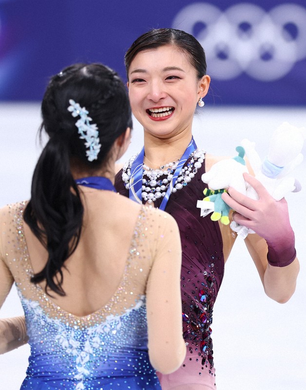 表彰式で顔をぬいぐるみで覆った後、笑顔を見せる銀メダルの坂本花織＝ミラノ・アイススケートアリーナで2026年2月19日、猪飼健史撮影