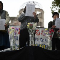 原爆ドーム前で行われたウクライナの平和を訴える集会で、献花された花束と祈りを捧げる参加者ら＝広島市中区で2026年2月24日午後3時51分、佐藤賢二郎撮影