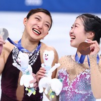 表彰式で銀メダルを手に笑顔を見せる坂本花織選手（左）と銅メダルの中井亜美選手＝ミラノ・アイススケートアリーナで2026年2月19日、猪飼健史撮影