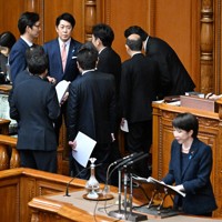 参院本会議で立憲民主党・斎藤嘉隆参院国対委員長の代表質問に対する高市早苗首相（右手前）の答弁について壇上に集まり協議する議員ら。左奥は佐藤啓官房副長官＝国会内で2026年2月26日午後2時48分、平田明浩撮影
