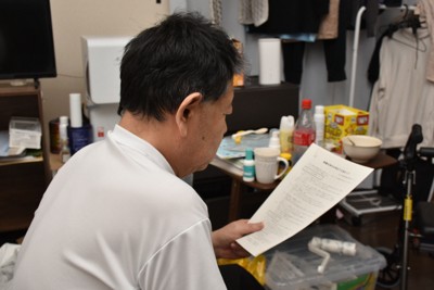 東京電力福島第1原発事故のため、福島県から岡山県に避難した中村裕昭さん。損害賠償に関する書類をみつめていた＝岡山市で2026年3月2日午後6時37分、砂押健太撮影
